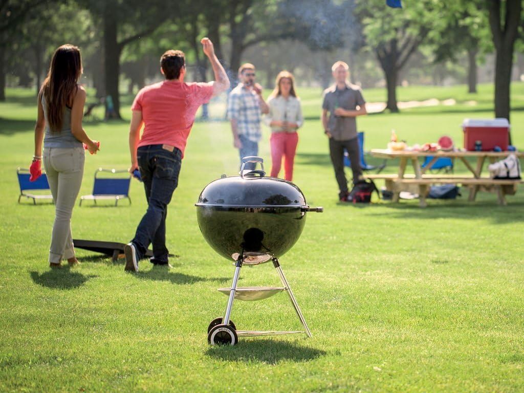 Weber 22″ kettle grill in action on a patio, with glowing charcoal and burgers sizzling on the grate.