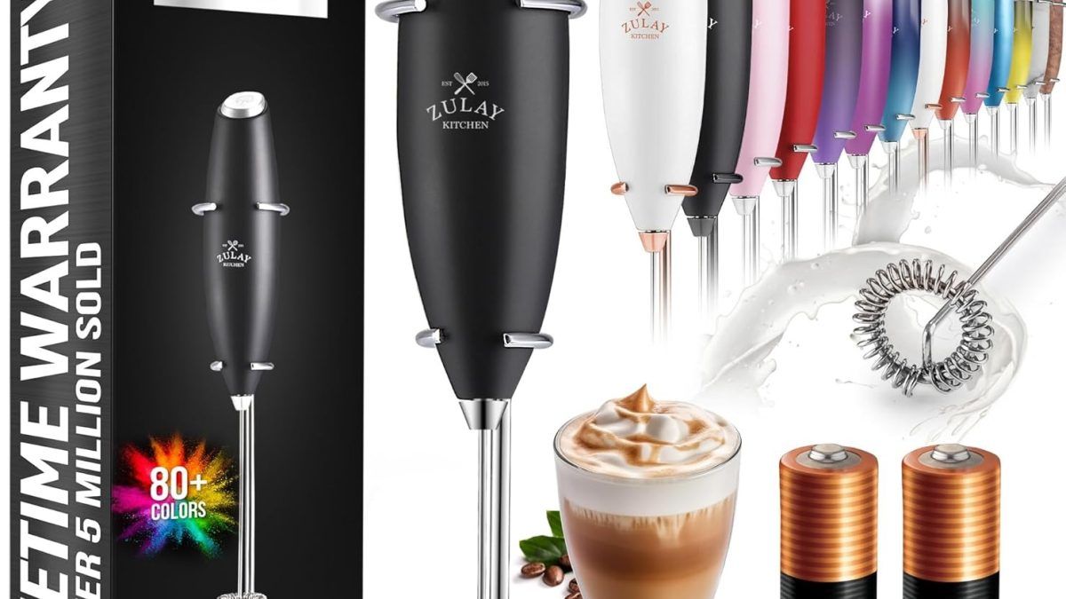 Stylish Zulay milk frother beside a cappuccino, highlighting its compact design and barista-level frothing power.
