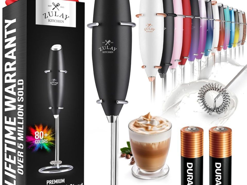 Stylish Zulay milk frother beside a cappuccino, highlighting its compact design and barista-level frothing power.