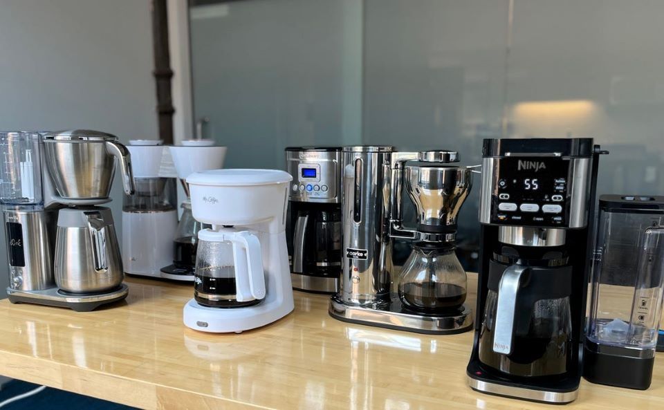 Modern coffee maker brewing fresh coffee in a home kitchen with steam rising.