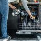 Modern dishwasher running a cleaning cycle with dishes inside kitchen unit.