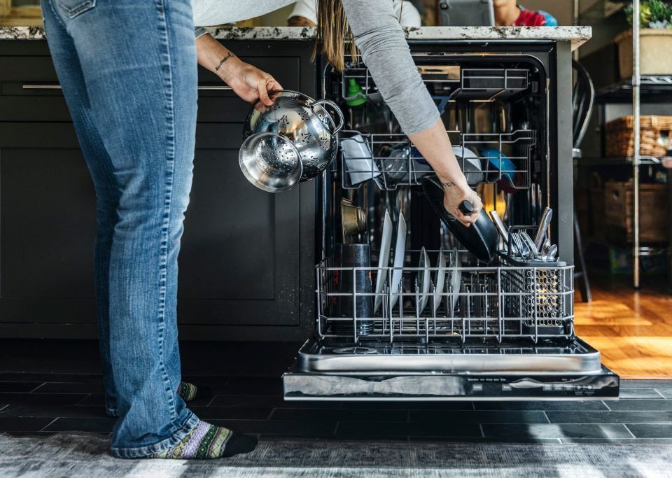 Modern dishwasher running a cleaning cycle with dishes inside kitchen unit.