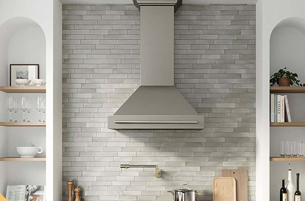 Wall-mounted kitchen ventilation hood with bright lights over gas stove.