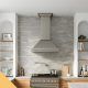 Wall-mounted kitchen ventilation hood with bright lights over gas stove.