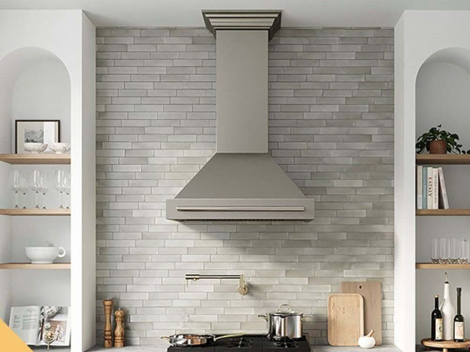 Wall-mounted kitchen ventilation hood with bright lights over gas stove.