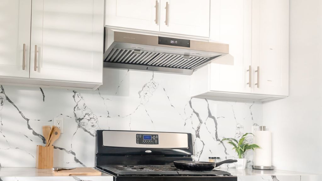 Modern stainless steel ventilation hood above stove in a clean kitchen.