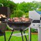 Outdoor barbecue grill with sizzling meat cooking on backyard patio.