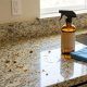 Person cleaning kitchen countertop with cleaner spray