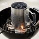 Chef adjusting top aluminum damper on black Weber Jumbo Joe portable grill.