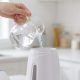 Person using an Oghom clothes steamer on a hanging shirt